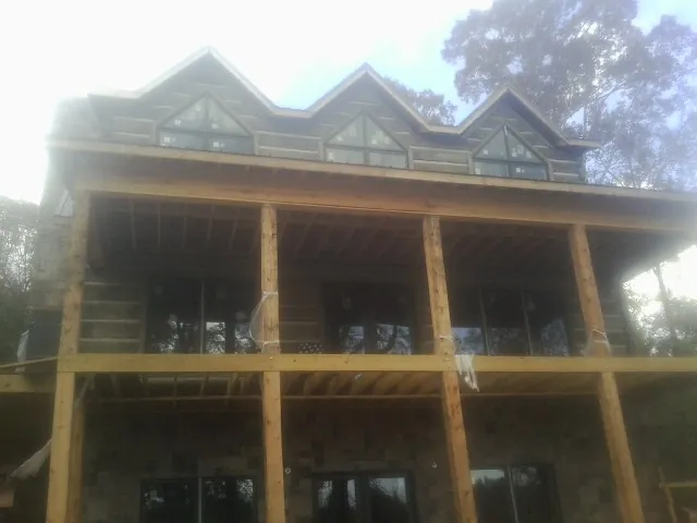 Dormers and porch framing on a large log home under construction — Roof Coating work by our crew in Crittenden
