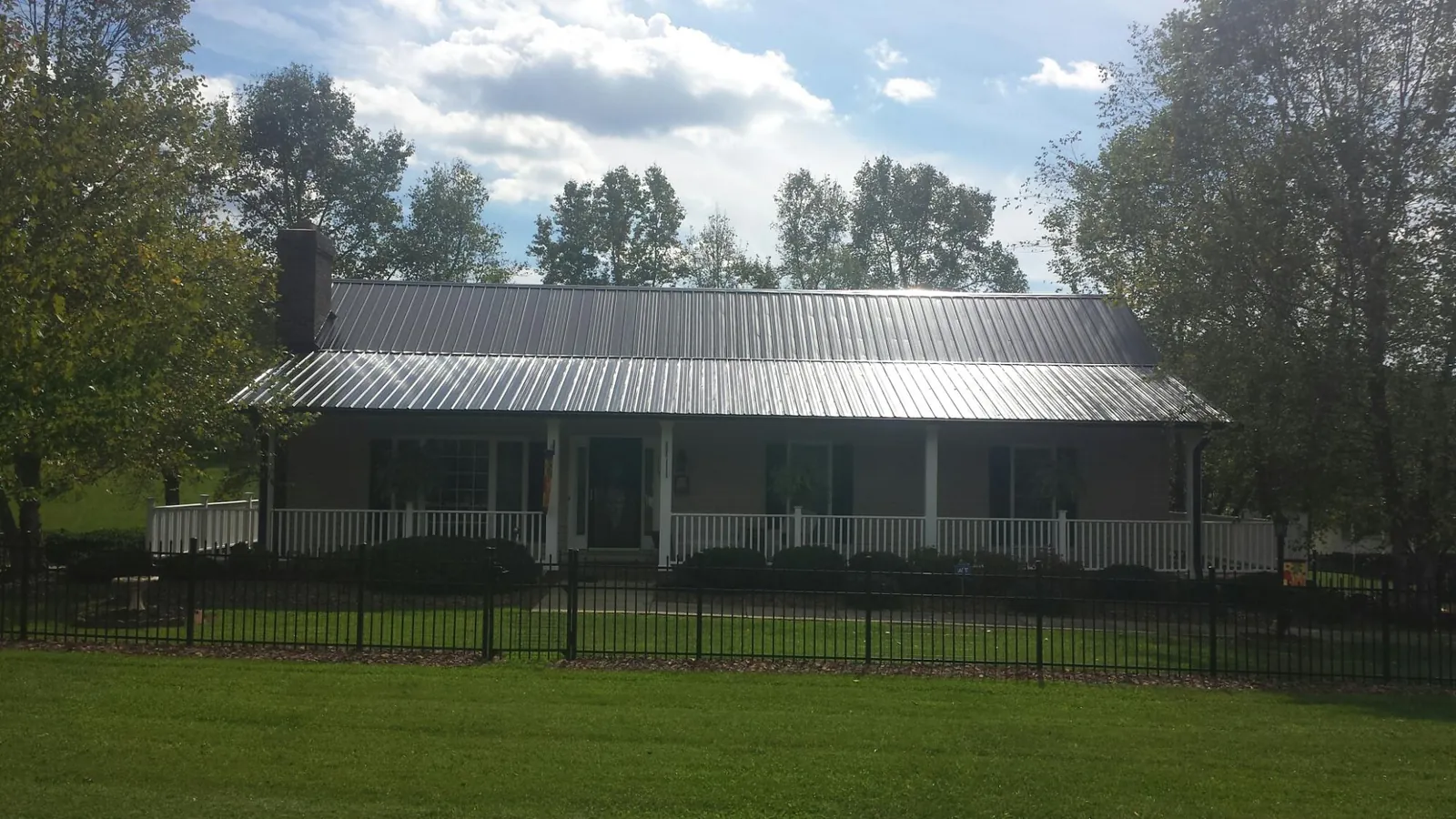 Gray metal roof on a brick ranch with a full width front porch — Gutter Guard Installation work by our crew in Crittenden