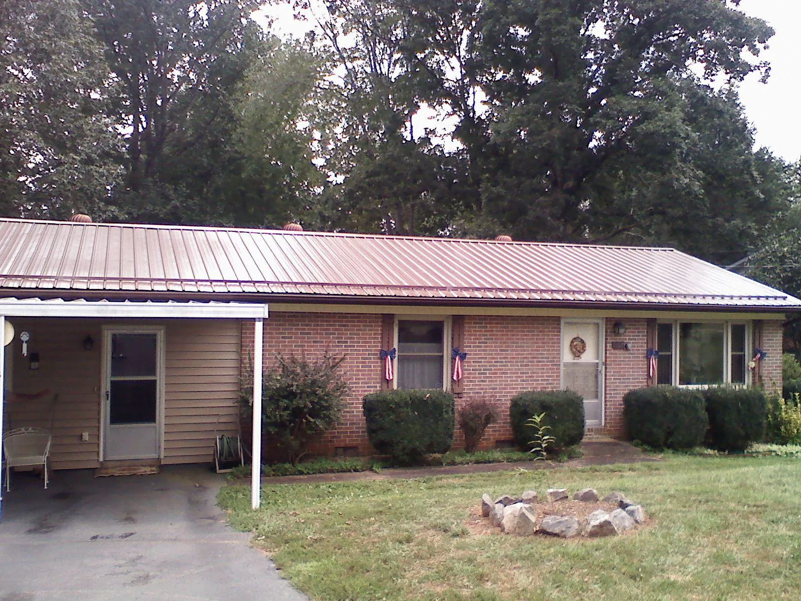 Bronze metal roof and carport on a brick ranch home — Roof Repair work by our crew in Crittenden