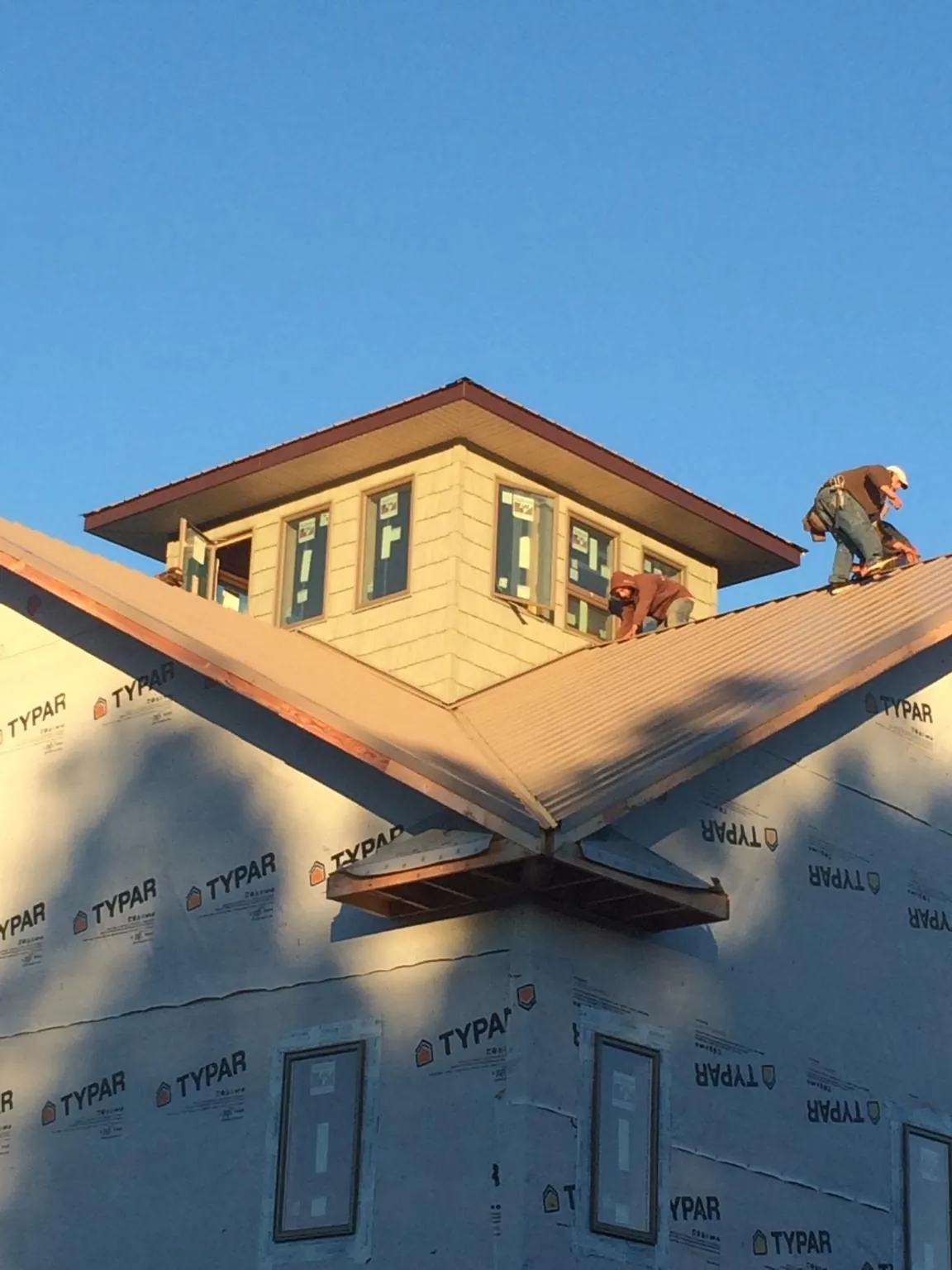 Roofers working around a rooftop cupola on a new metal roof at sunset — Roof Waterproofing in Crittenden by Roofing Brothers
